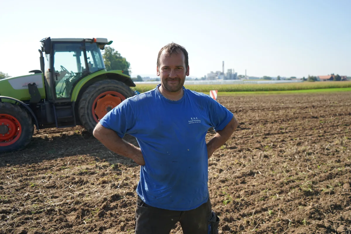 Hans Kunz steht vor seinem Traktor auf dem Acker.